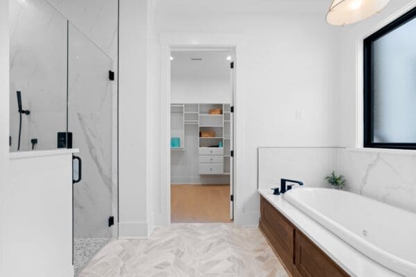 Modern bathroom with white tiles and wooden bathtub panel.