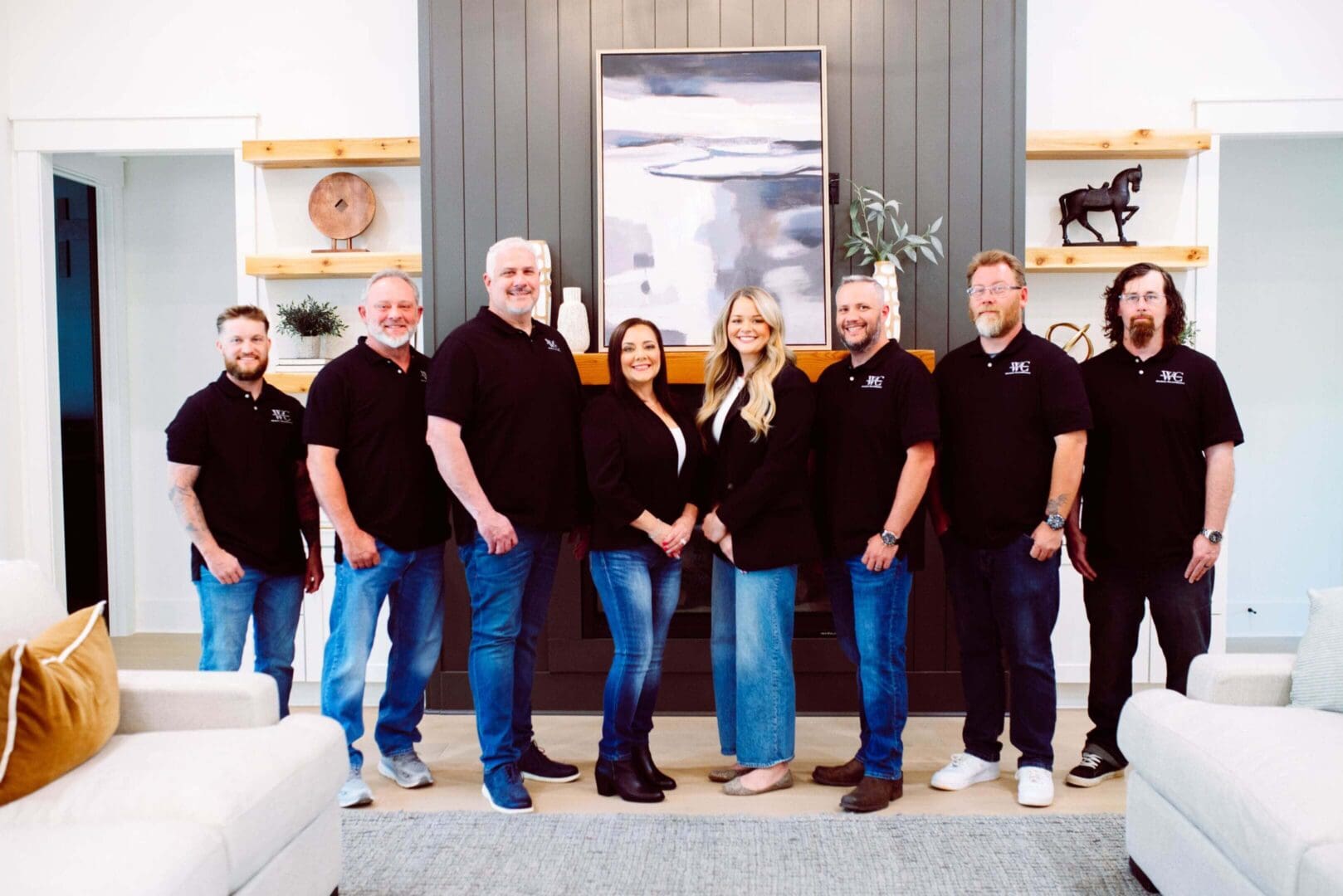 A group of people in matching black shirts posing indoors.