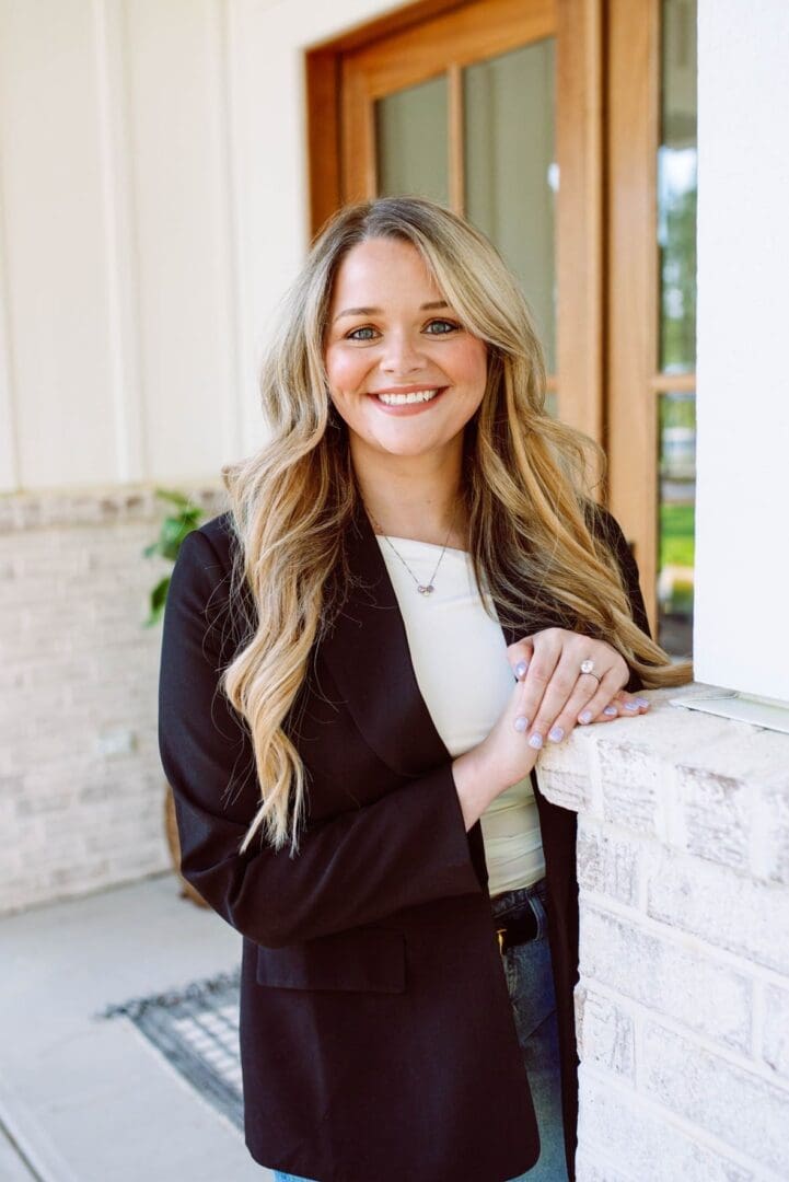 A smiling woman with long blonde hair wearing a black blazer and white top.