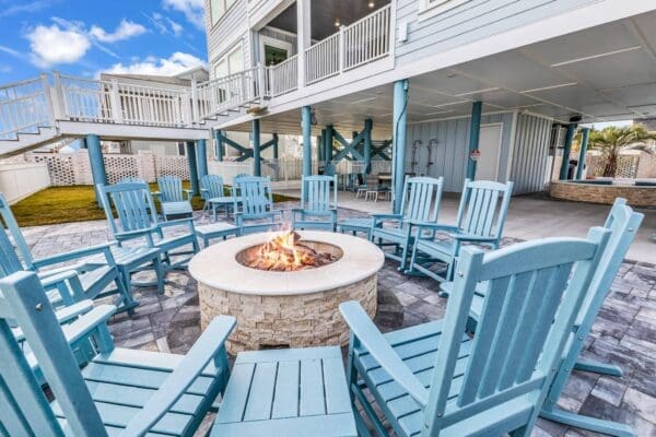 Cozy outdoor seating with blue chairs around a fire pit on a wooden deck.