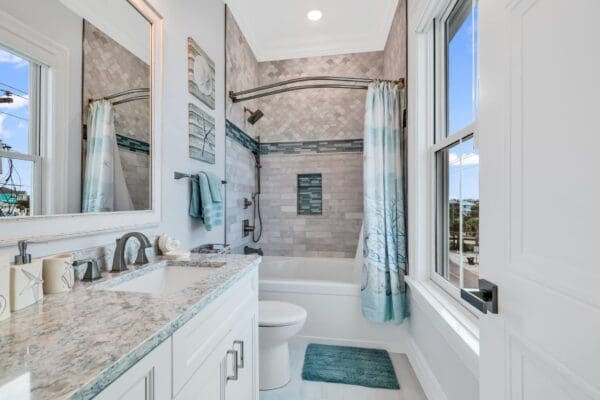 Bright bathroom with white vanity, bathtub, and patterned tile shower.