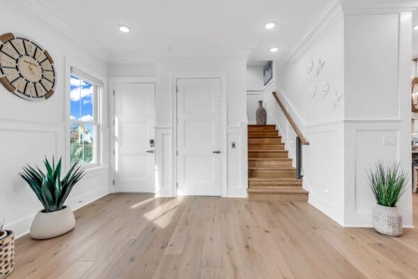 Bright white entryway with wooden stairs and natural light.