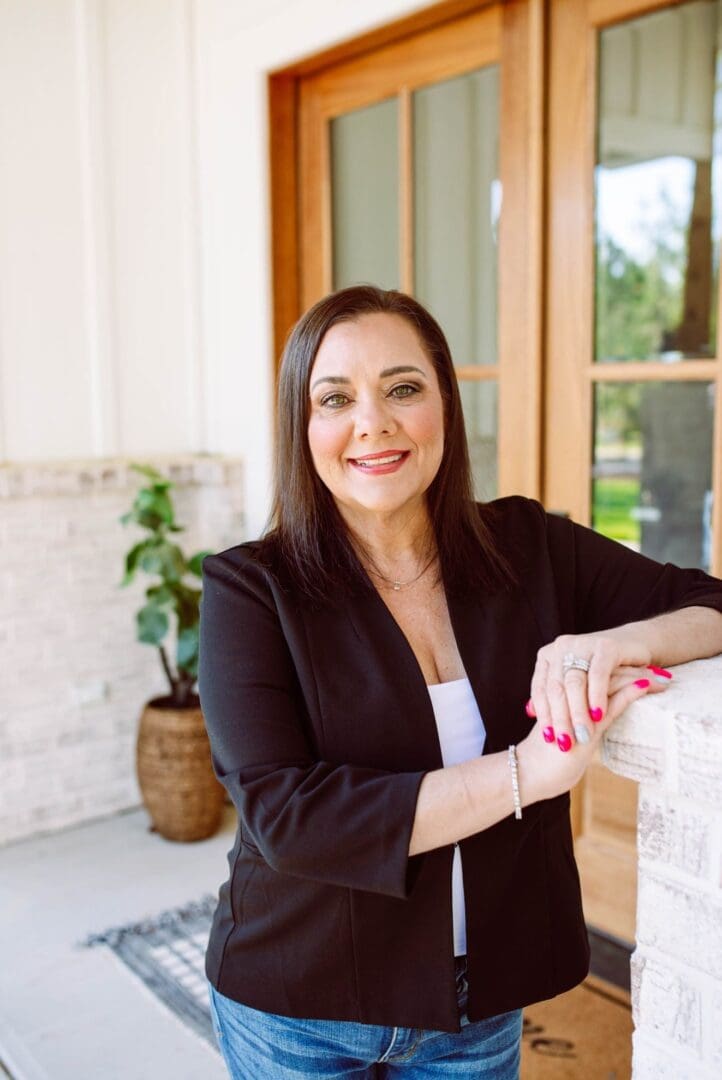 Confident woman in business attire smiling on a porch.