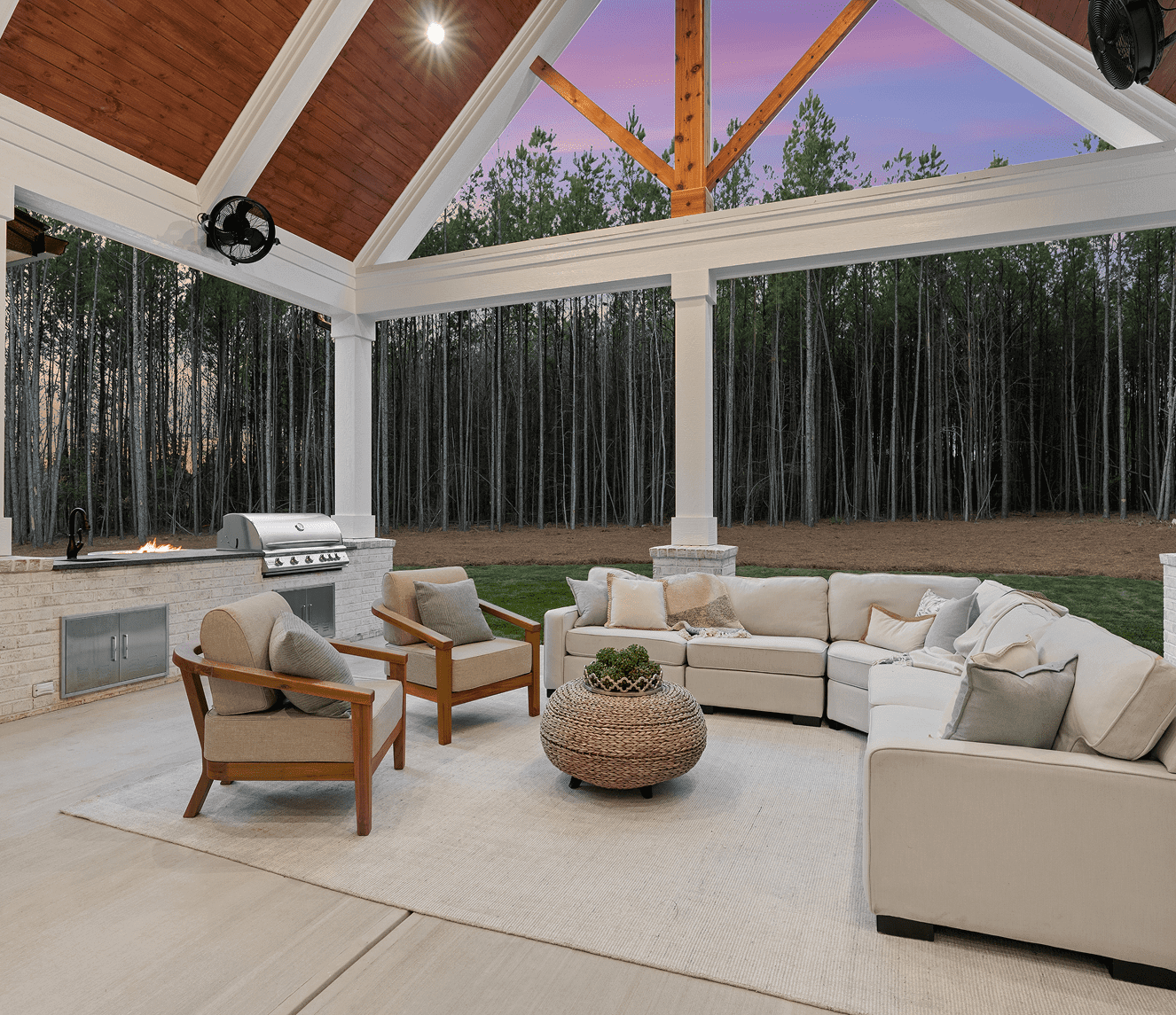 Cozy outdoor seating area with comfortable sofas and armchairs under a wooden pergola.